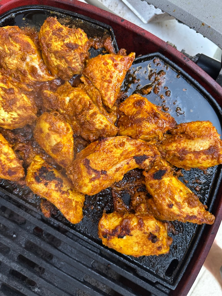 Juicy tandoori chicken cooked on a BBQ hot plate with smoky, charred edges—easy camping recipe.