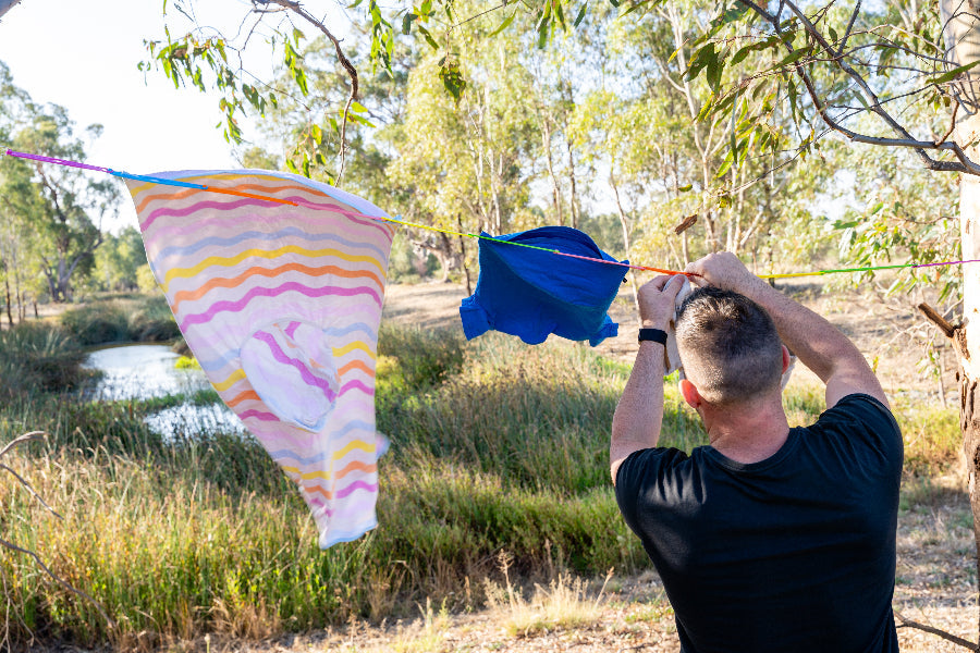 Rainbow pegless clothesline holding washing in the wind at a campsite